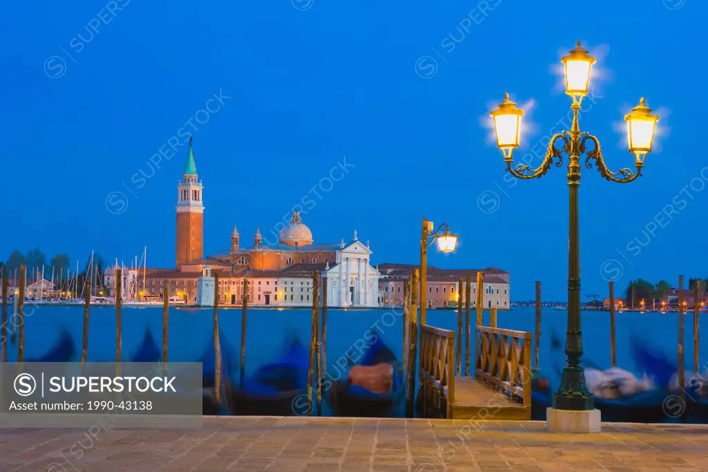 Gondolas with the church of Saint George Major in the distance at night, Venice, Italy