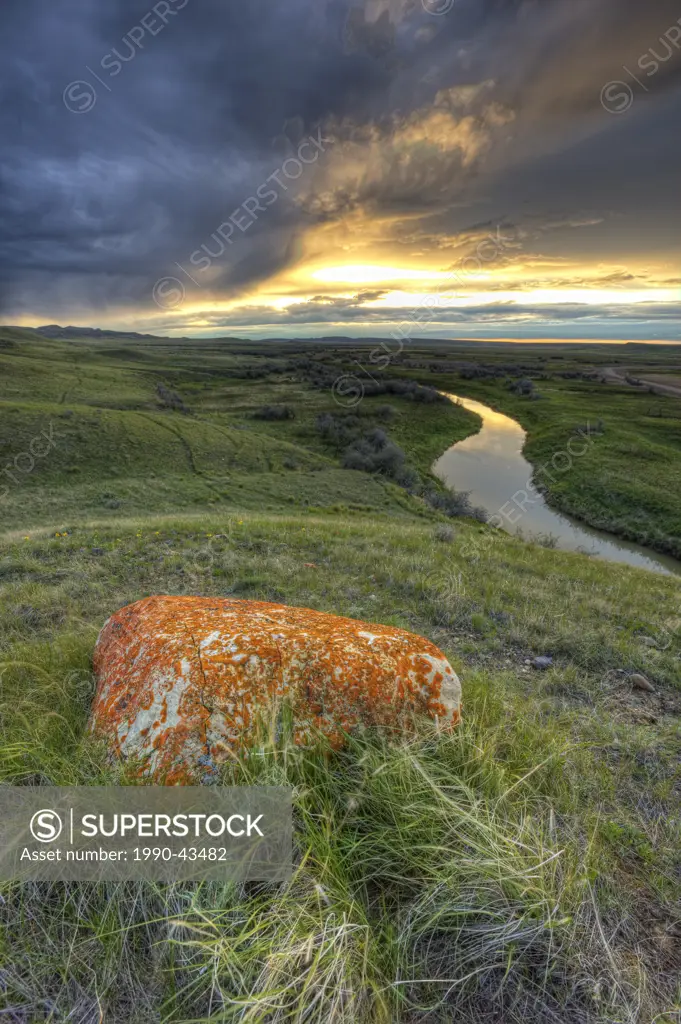 HDR view of a glacial erratic and storm clouds at sunset over the Frenchman River Valley, Grasslands National Park, Saskatchewan.
