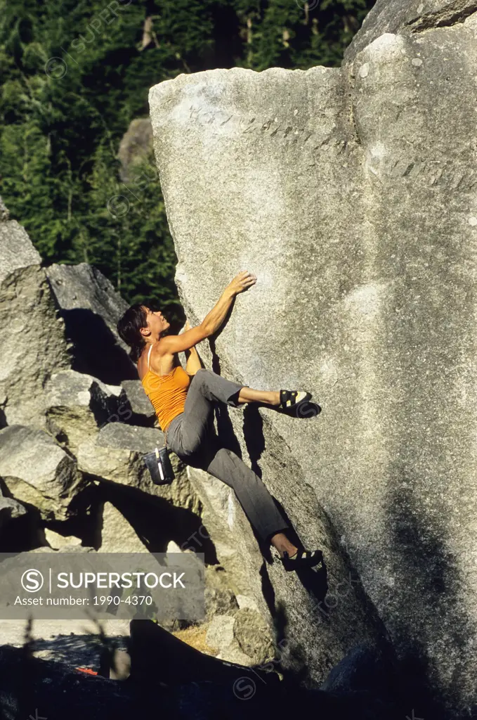Woman bouldering on Gull Skull, V6, Apron Boulders, Squamish, British Columbia, Canada.