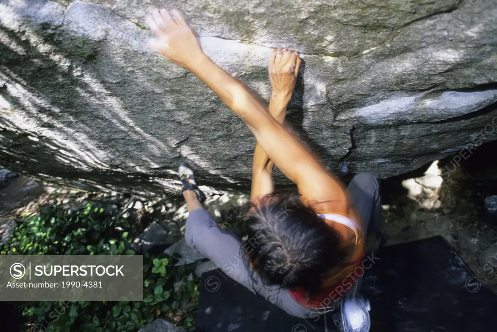 Woman bouldering on Siddhartha, V10, Apron Boulders, Squamish, British Columbia, Canada.