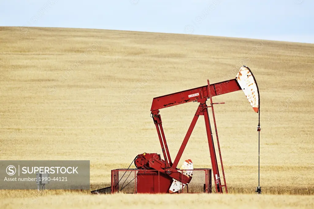 Oil well pump jack in wheat field. Gull Lake, Saskatchewan, Canada.