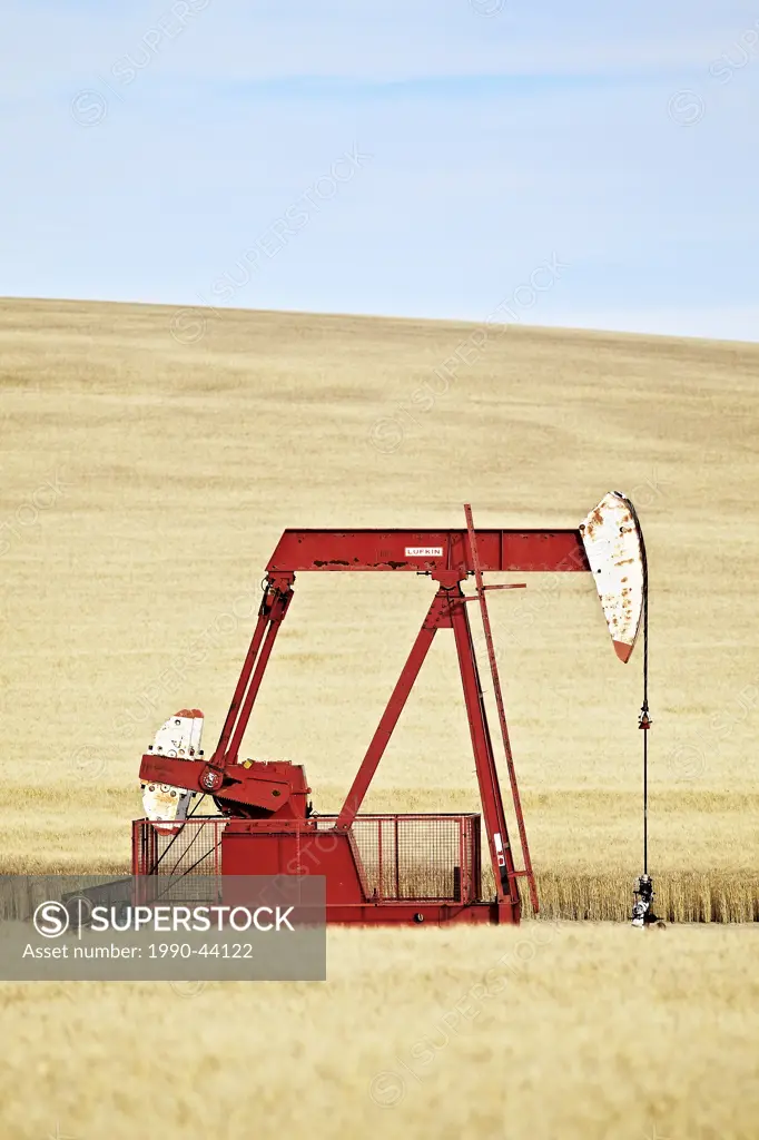 Oil well pump jack on prairie wheat field. Gull Lake, Saskatchewan, Canada.