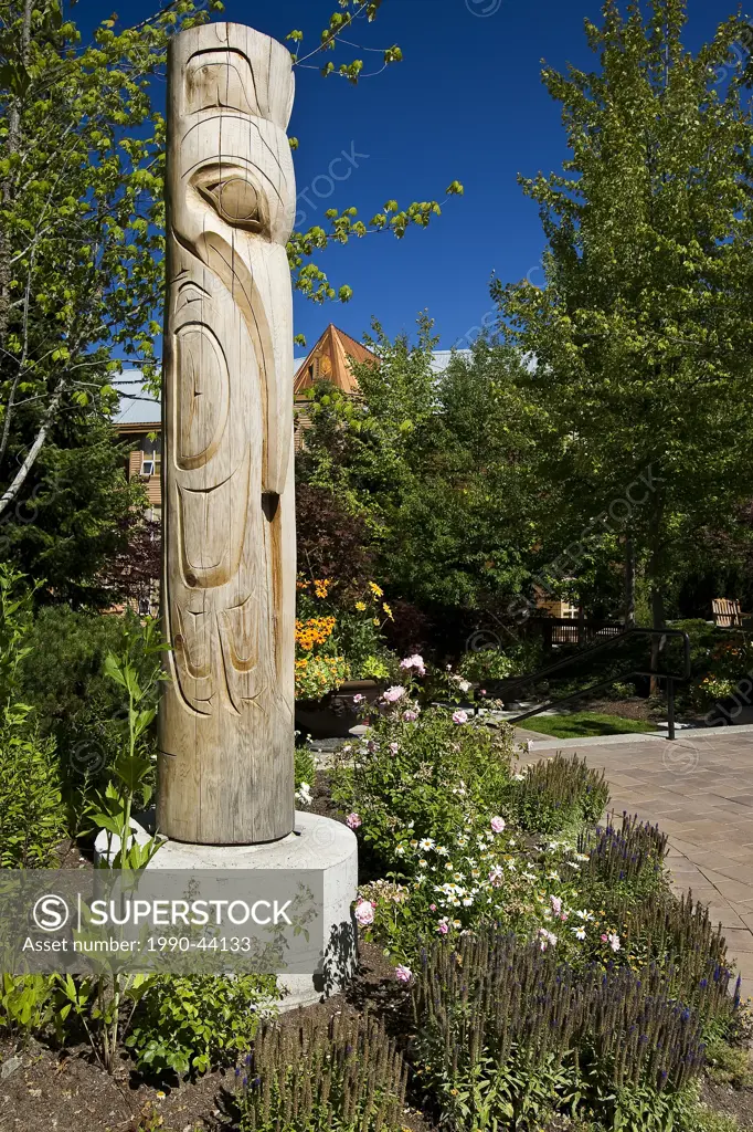 Totem Pole in flower bed on sunny day, Whistler, British Columnbia, Canada