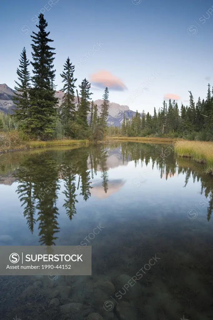Lenticular Clouds above mountain range and reflected in open water, Jasper National Park, Alberta, Canada