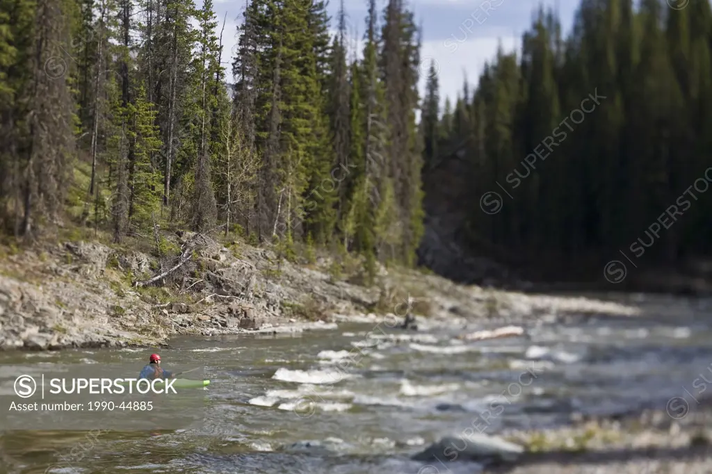 An older man whitewater kayaking on the Oldman River, Alberta, Canada