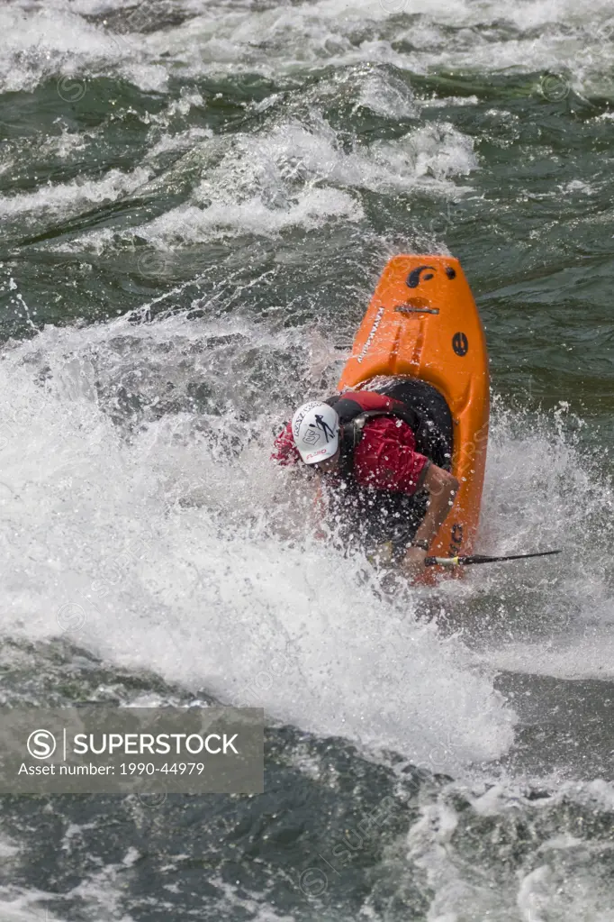 A male kayaker playboating on Pink Mountain wave on the Clearwater River, Clearwater, British Columbia, Canada