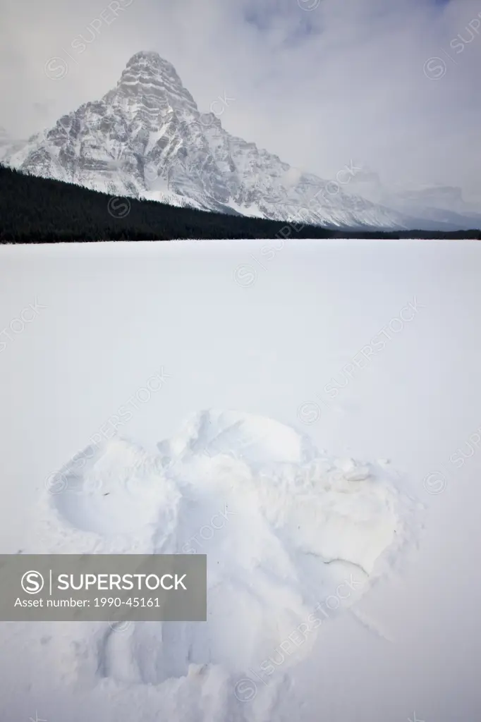 Snow angel on Waterfowl Lake after fresh snowfall during winter with Mount Chephren 3307 metres/10850 feet in background, Alberta, Canada.
