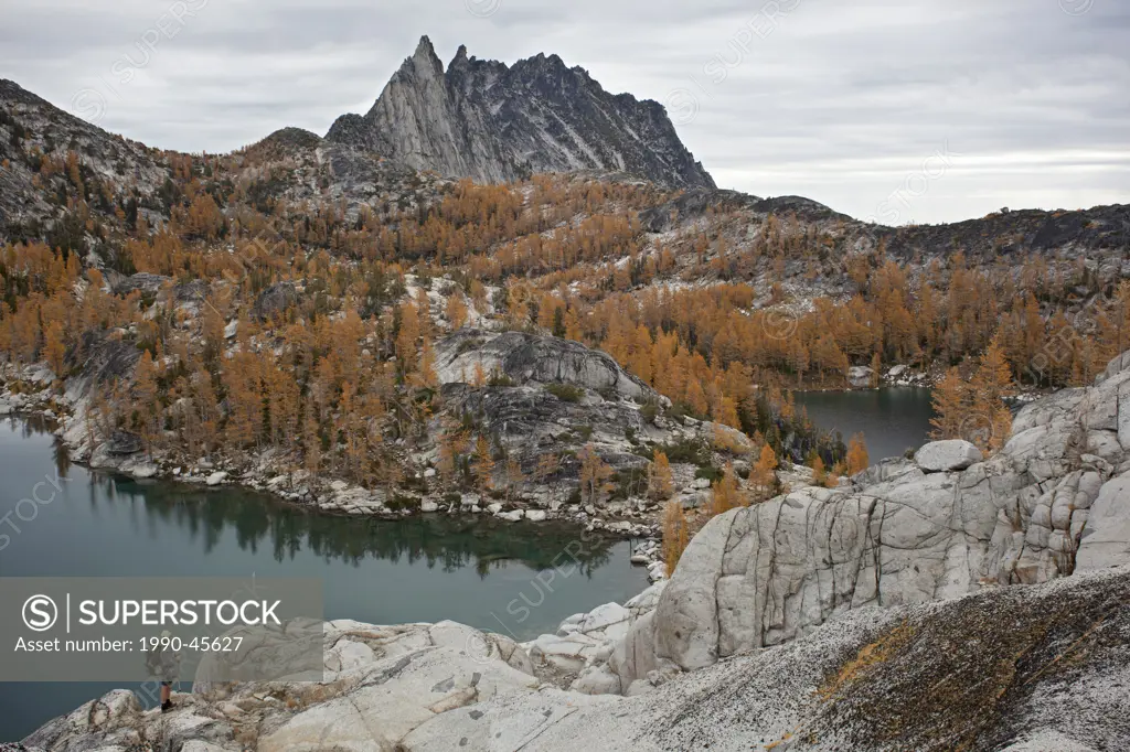 Hiker overlooking Inspiration and Perfection Lakes and Prusik Peak in the Upper Enchantments Basin, Alpine Lakes Wilderness, Washington State, United ...
