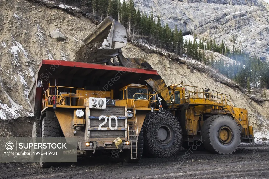 A large bucket loader loading soil into an off road haul truck at a coal mine site, Alberta, Canada.