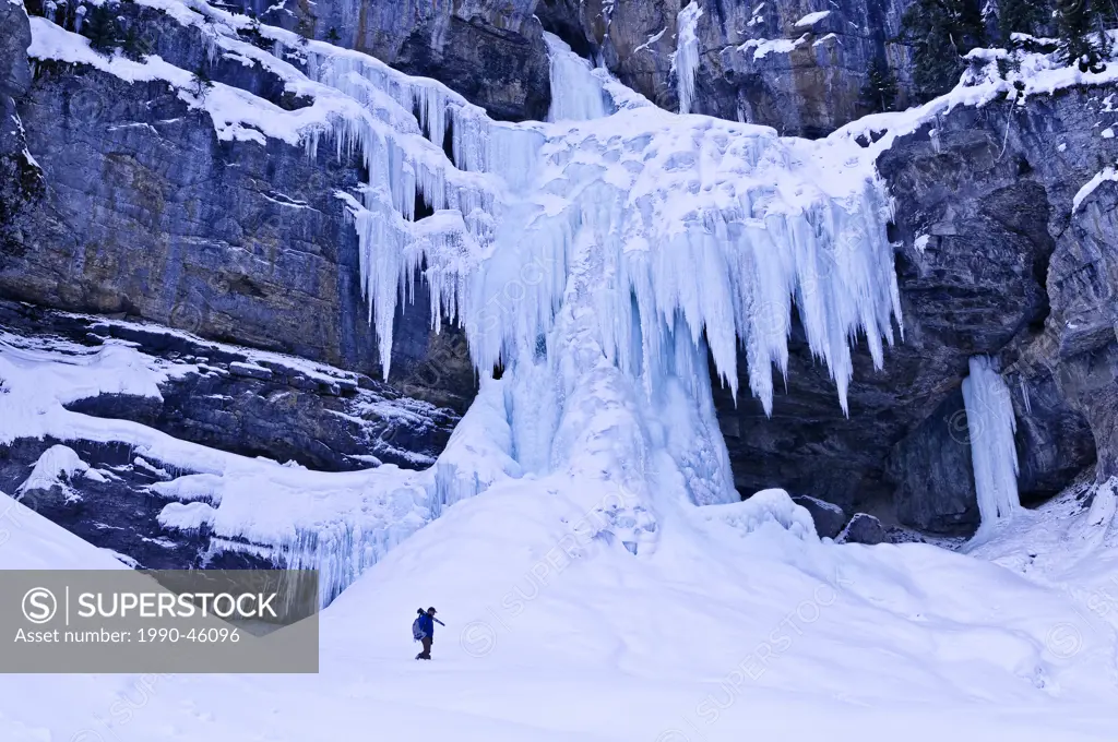 Photographer dwarfed by frozen Panther Falls in Winter, Banff National Park, Alberta, Canada