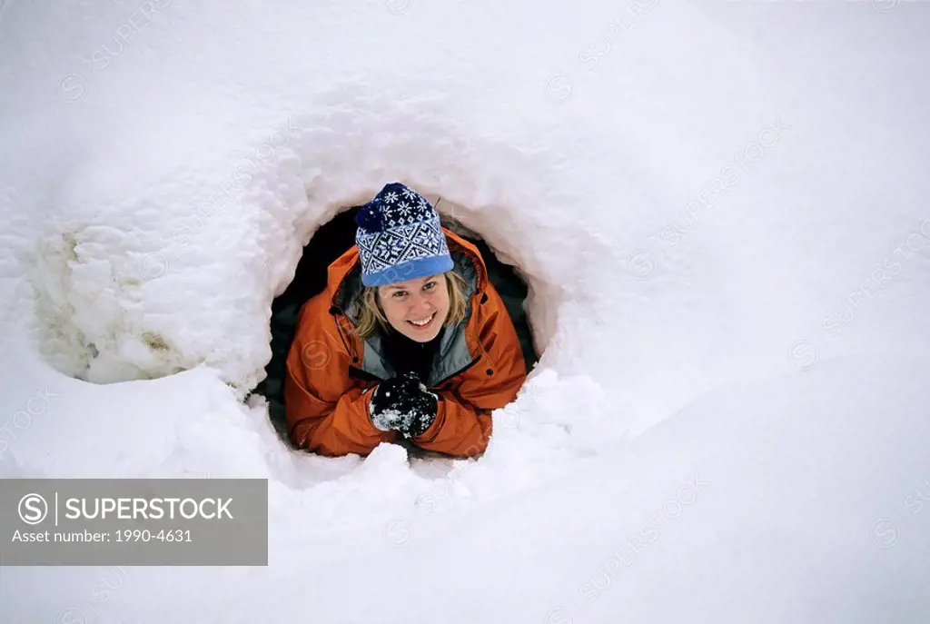 A woman crawls out of a ´Quinze´ snow hut, in Algonquin Provincial Park, Ontario, Canada
