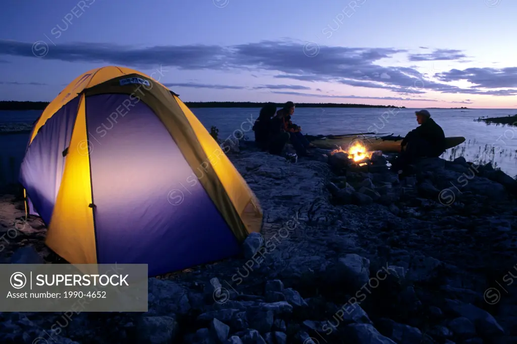 Campers enjoy a fire on the shore of Lake Huron at sunset, near the town of Tobermory, Bruce Peninsula, Ontario, Canada
