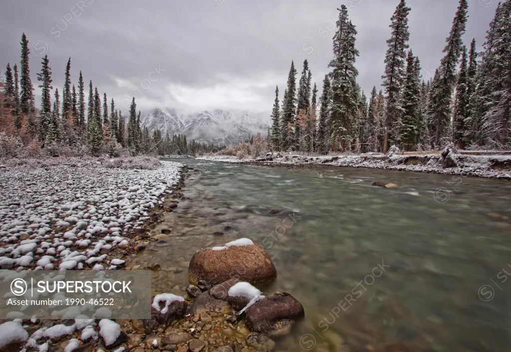The Wheaton River continues to run with the snow coating the rocks, trees and mountains, Yukon, Canada.