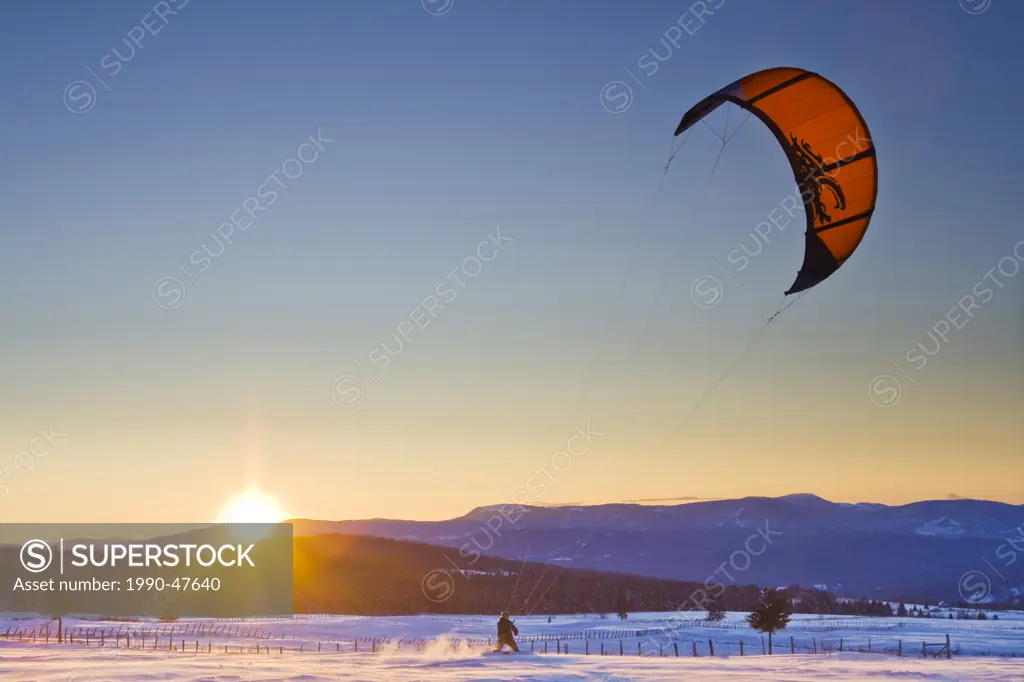 Kiteboarder with sun setting behind the mountains in the distance. Location: Rural route Saint_Marie, Charlevoix, Quebec, Canada.