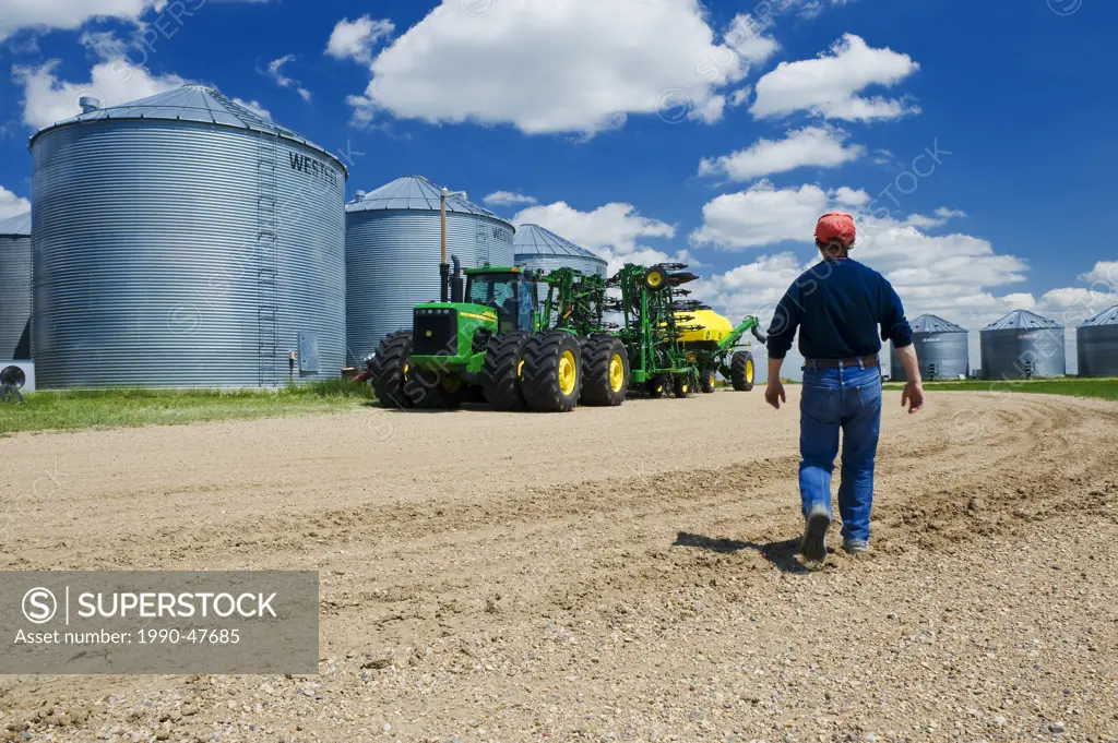 A man walks toward seeding equipment in farmyard near Torquay Saskatchewan, Canada