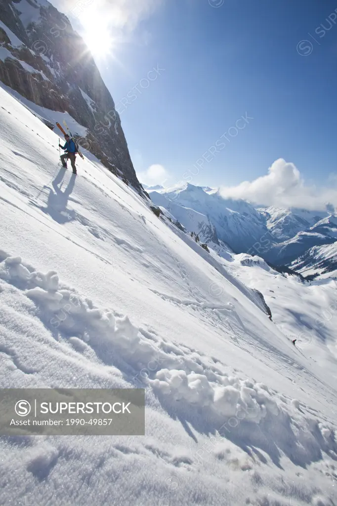 A male ski mountaineer bootpacks up a steep exposed slope. Icefall Lodge, Golden, British Columbia, Canada