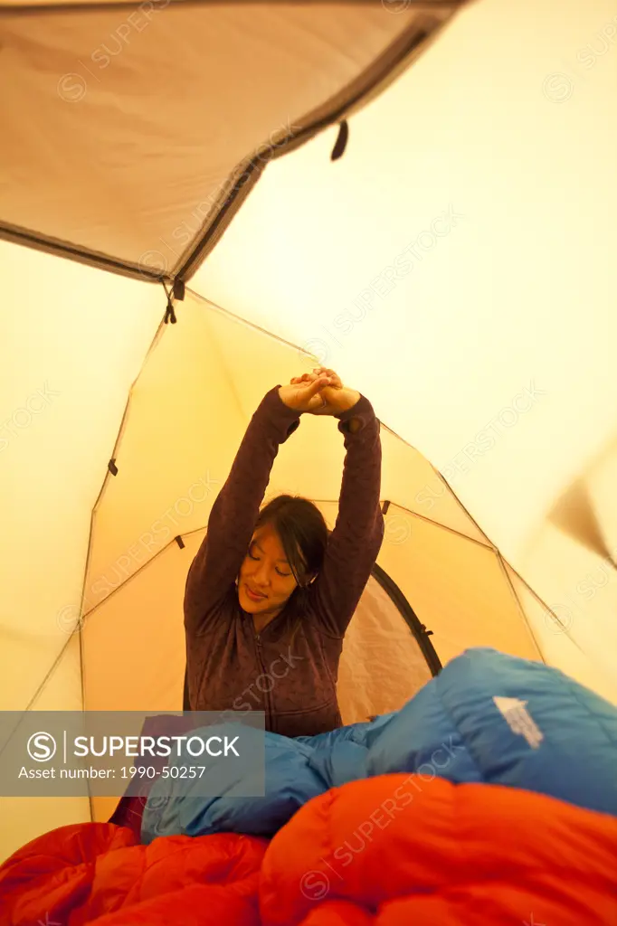 A young woman waking up while camping in Jasper Provincial Park, Alberta, Canada