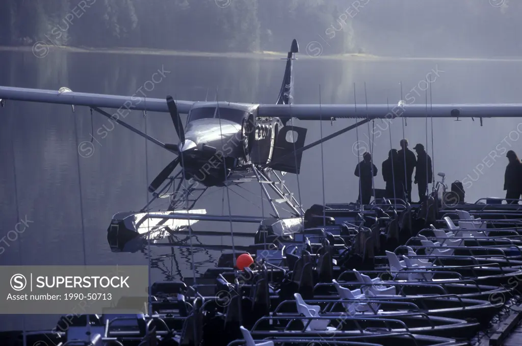 Float plane waits at the dock in the early morning mist at a Queen Charlotte Islands floating fishing lodge in northern British Columbia, Canada