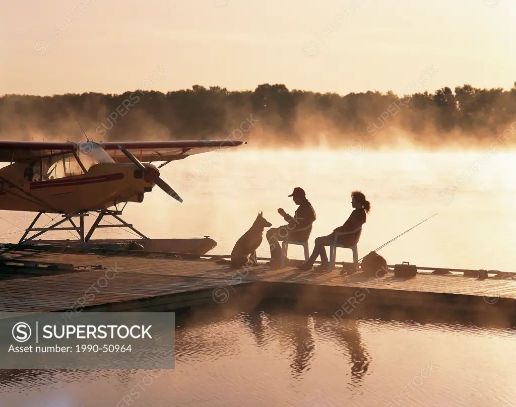 couple on dock in early morning mist, along Red River, north of Selkirk, Manitoba, Canada.
