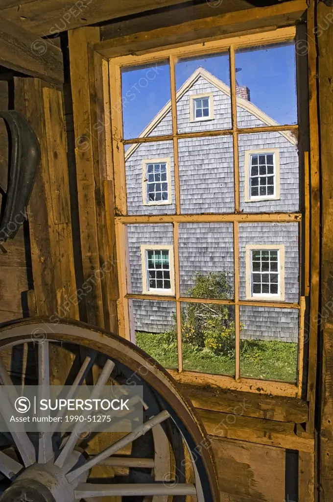 View of farmhouse through barn window at Historic Acadian Village in West Pubnico, along the Acadian Shores and Atlantic Ocean in Nova Scotia, Canada.