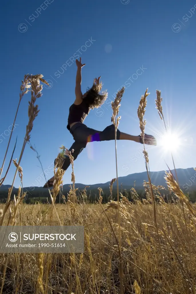 Female dancer in a grassy field with sun shining, British Columbia, Canada.