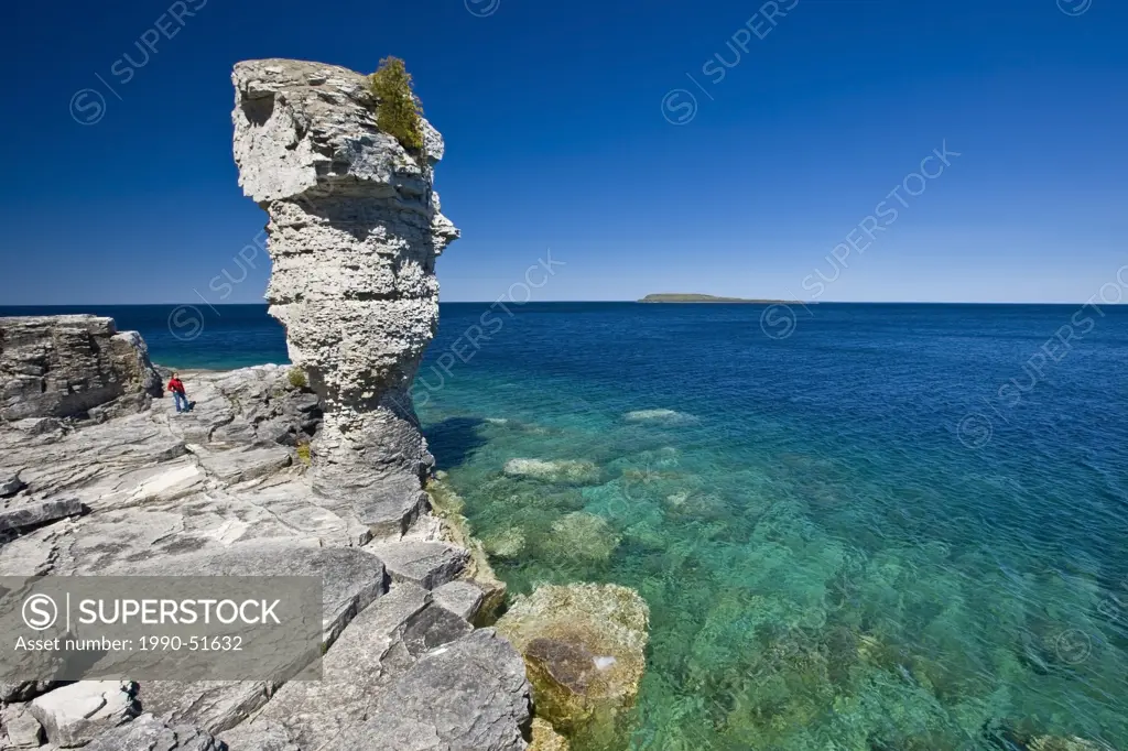 Person next to sea stack along the shoreline of Flowerpot Island in the Fathom Five National Marine Park, Lake Huron, Ontario, Canada