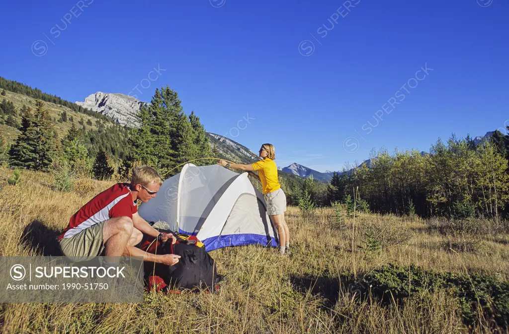 Couple setting up a tent in the Canadian Rockies, Alberta, Canada.