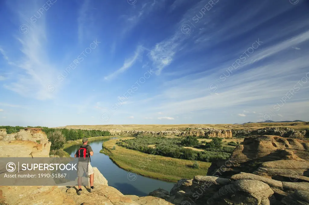 Hiker looking out over the Milk River Valley from the badlands hoodoos in Writing_on_Stone Provincial Park, Alberta, Canada.