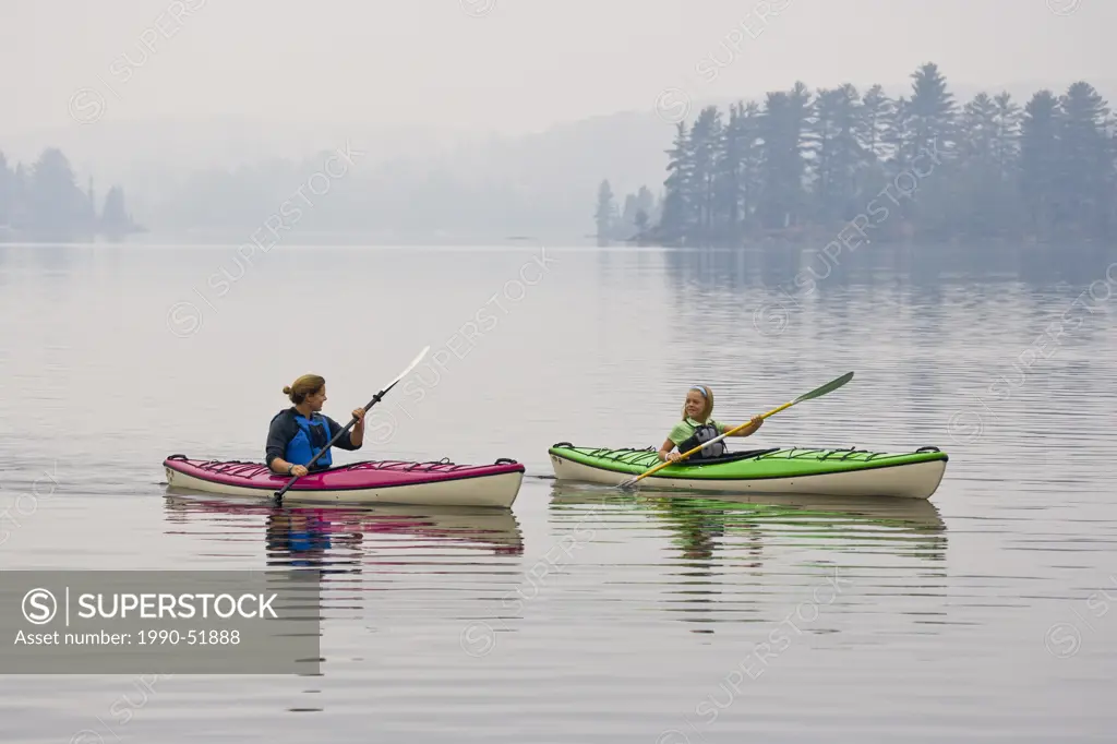 Young/middle_aged mother and daughter sea_kayaking on Source Lake, Algonquin Provincial Park, Ontario, Canada.