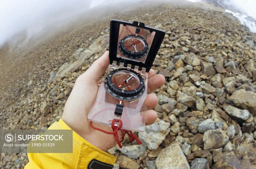 Hiker holding compass, Hudson Bay Mountain, Smithers, British Columbia, Canada.
