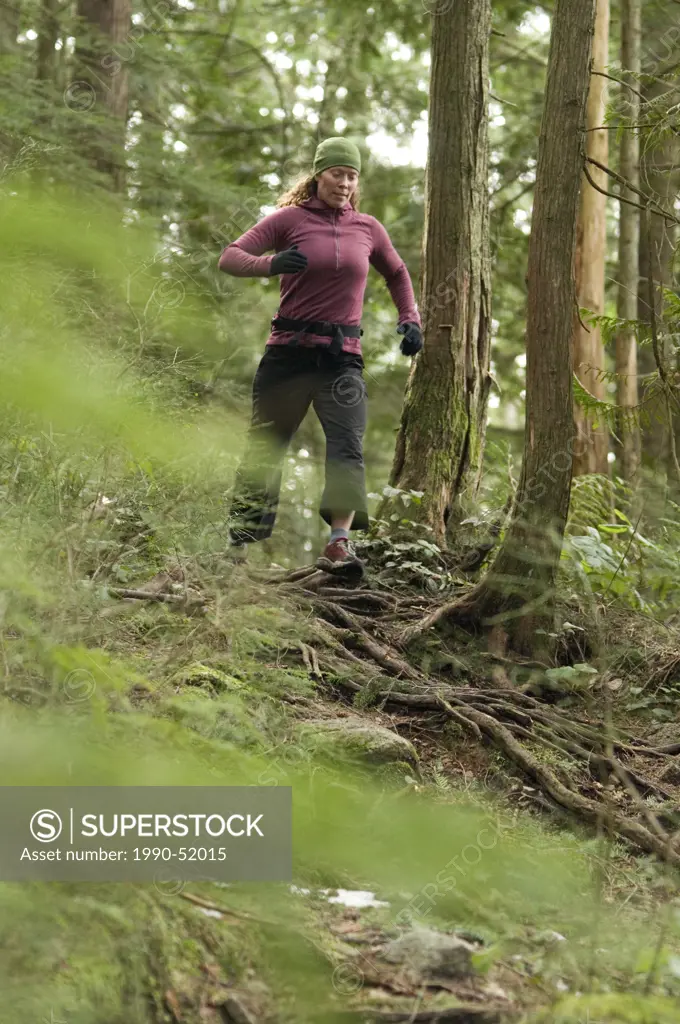 Young woman running on the Diez Vistas Trail. Buntzen Lake Regional Park. Port Moody, British Columbia, Canada