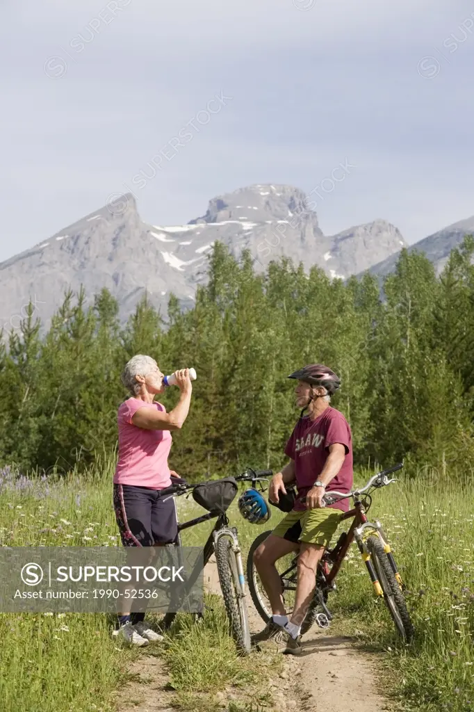 Active, fit, elderly couple mountain biking on trail in Fernie, British Columbia, Canada.