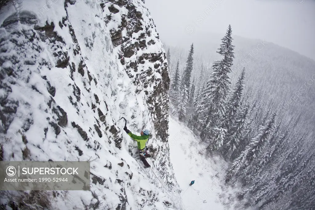 A strong female ice climber works her way up Snowline WI4, Even Thomas Creek, Kananaskis, Alberta, Canada