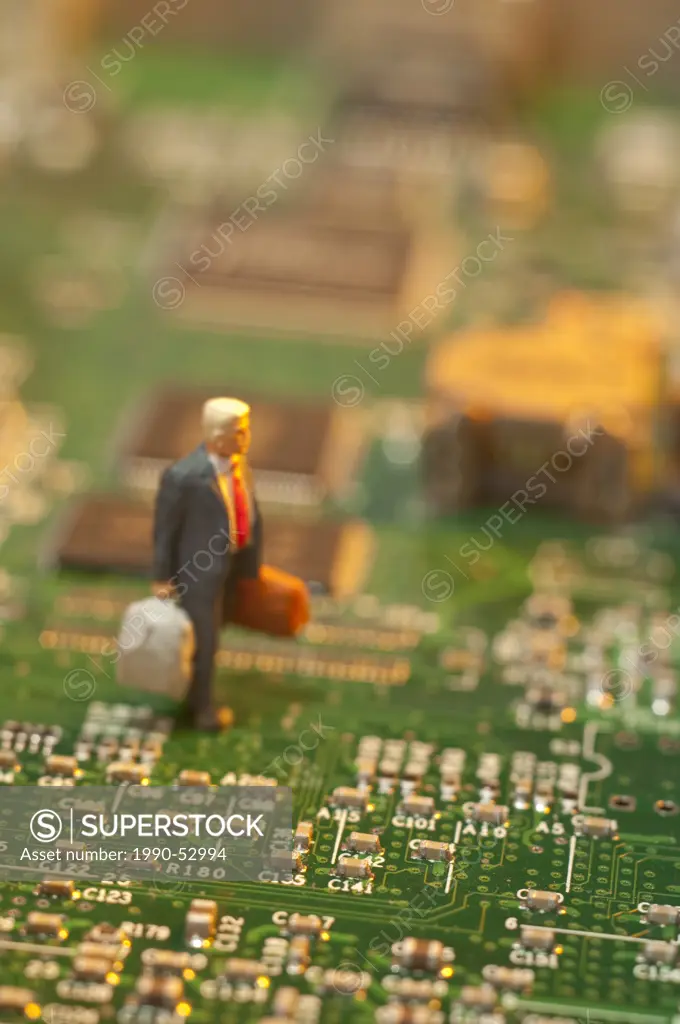 Miniature businessman figurine on computer circuit board