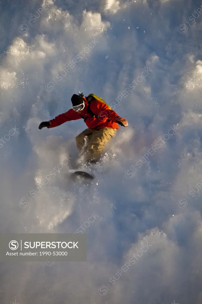 A backcountry snowboarder rides his sluff like a surf wave, Healy Pass, Banff National Park, Alberta, Canada