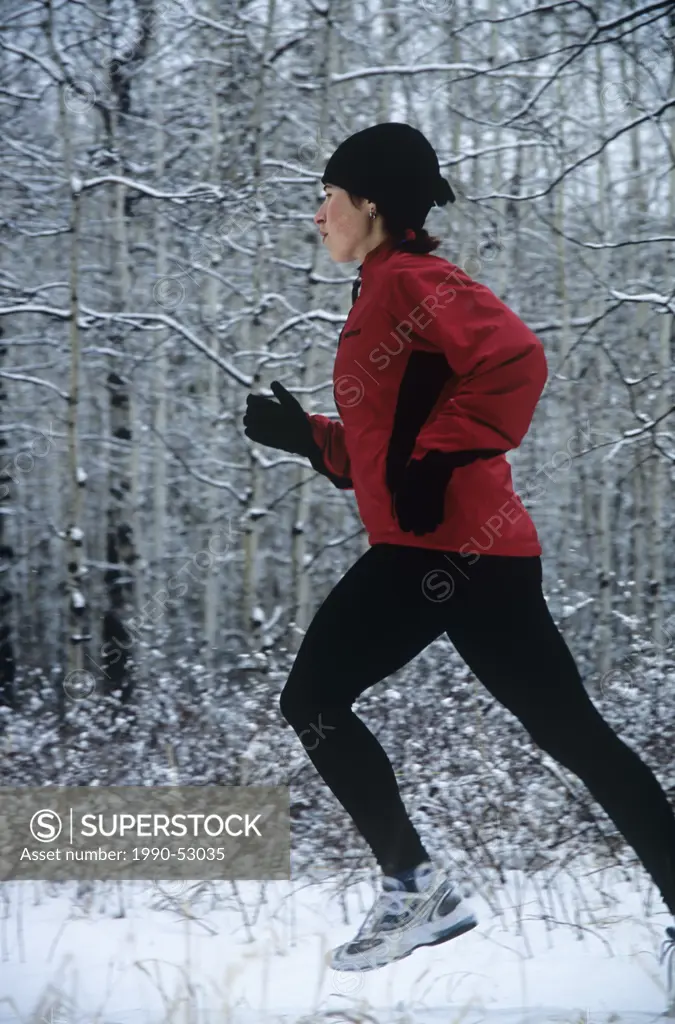 Woman running in winter, Canmore, Alberta, Canada.