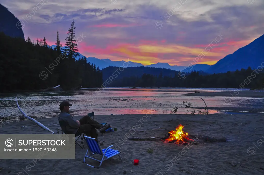 Man sitting at campfire, Dean River, British Columbia, Canada