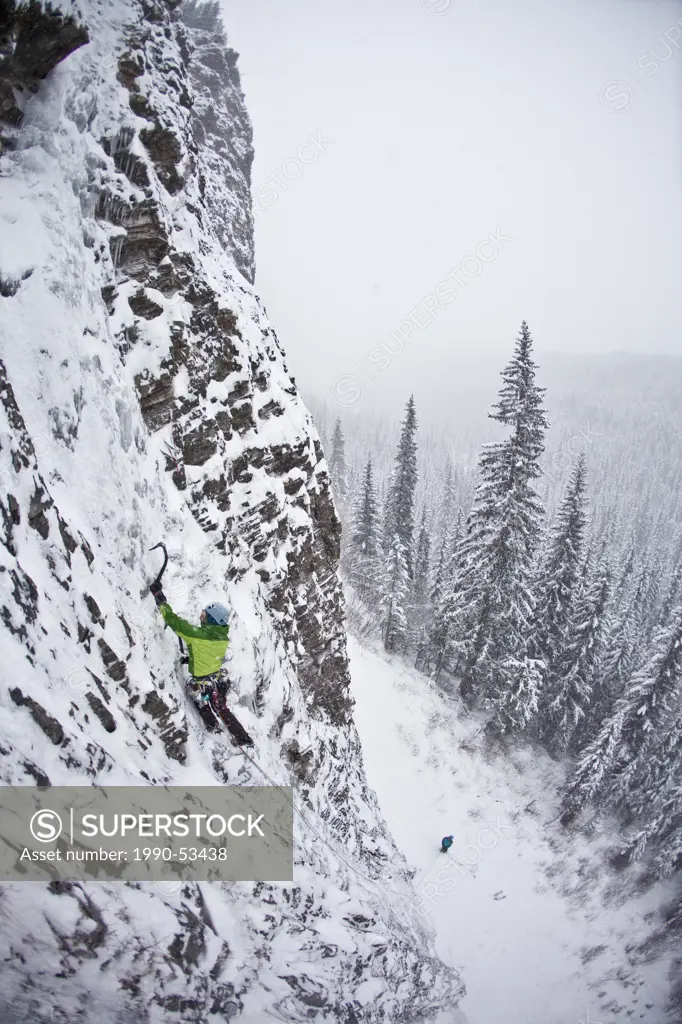 A strong female ice climber works her way up Snowline WI4, Even Thomas Creek, Kananaskis, Alberta, Canada