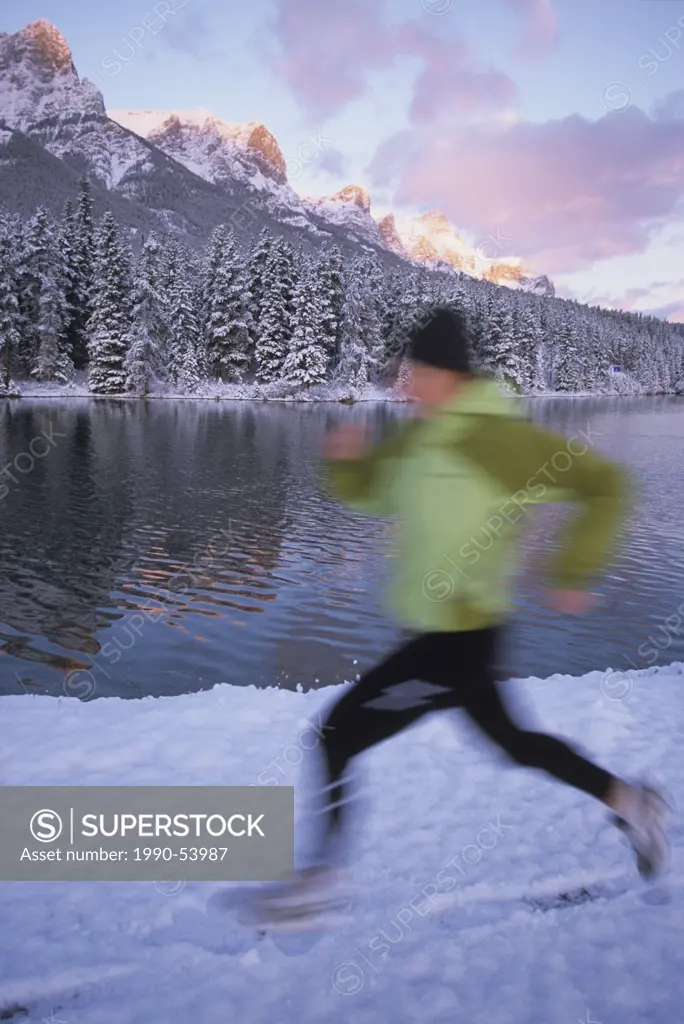 a young woman trail running in the winter on fresh snow in Canmore, Alberta, Canada.