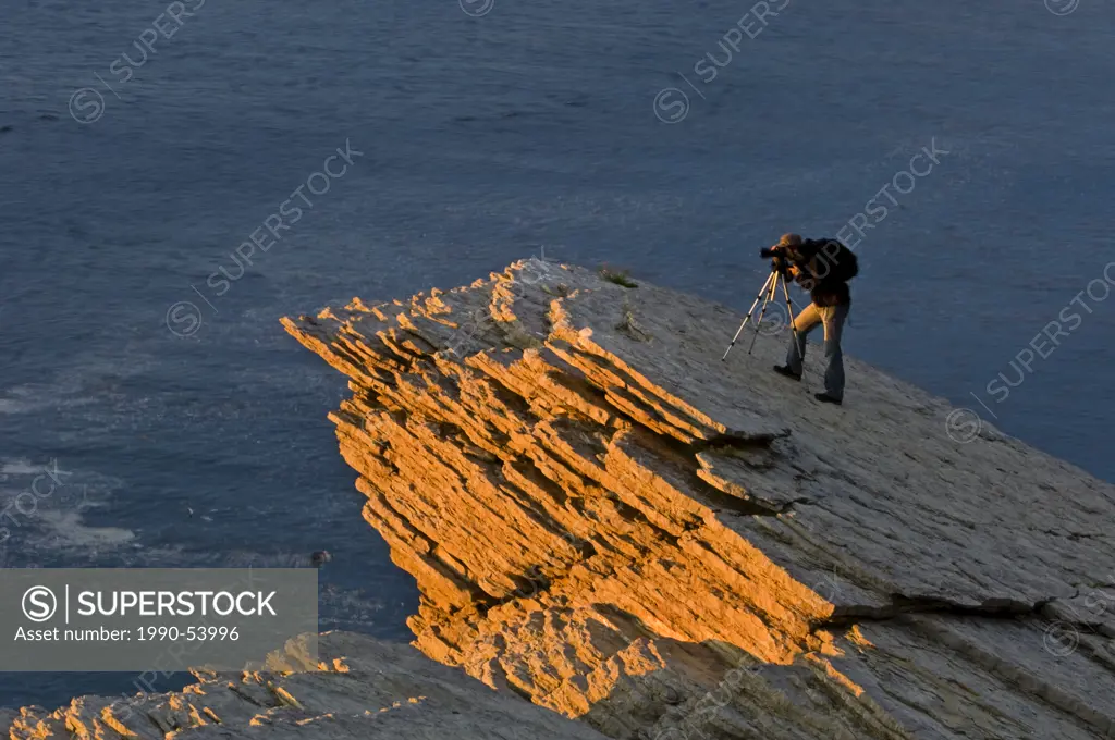 Cliffs of Cap_Bon_Ami and photographer at dawn. Forillon National Park, Gaspe Peninsula, Gaspe Cap des Rosiers, Quebec, Canada.