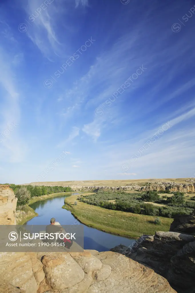 Hiker looking out over the Milk River from amid the hoodoos in Writing_on_Stone Provincial Park, Alberta, Canada.