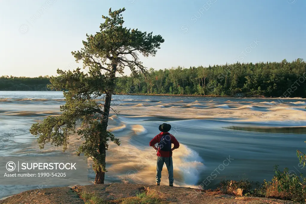 hiker along the Winnipeg River at Sturgeon Falls, Whiteshell Provincial Park, Manitoba, Canada.