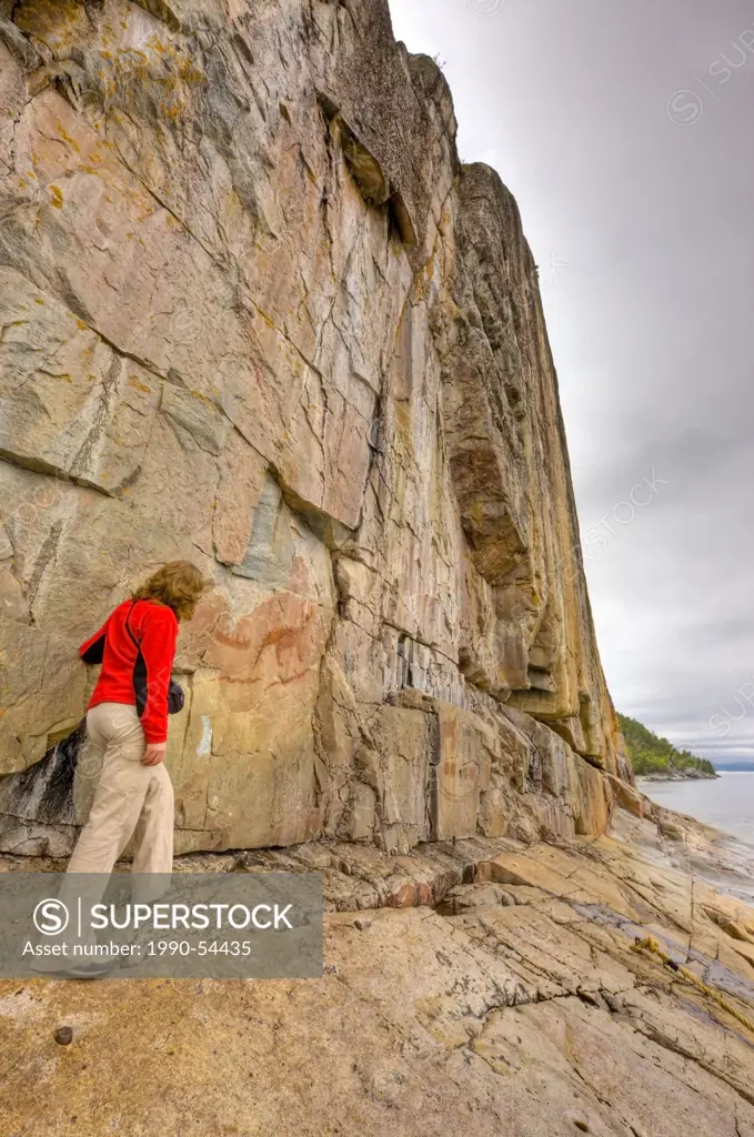 Tourist viewing the ancient pictographs on Agawa Rock, Agawa Rock Pictographs Trail, Lake Superior, Lake Superior Provincial Park, Ontario, Canada