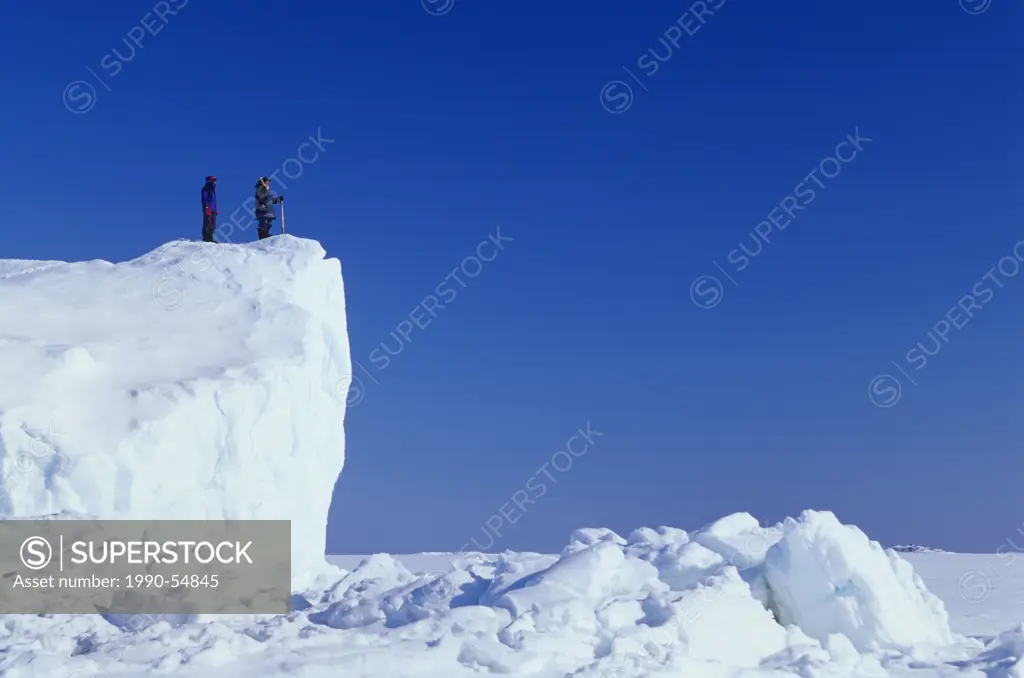 Inuit guide and client on iceberg frozen in sea ice, Kimmirut, Baffin Island, Nunavut, Canada.