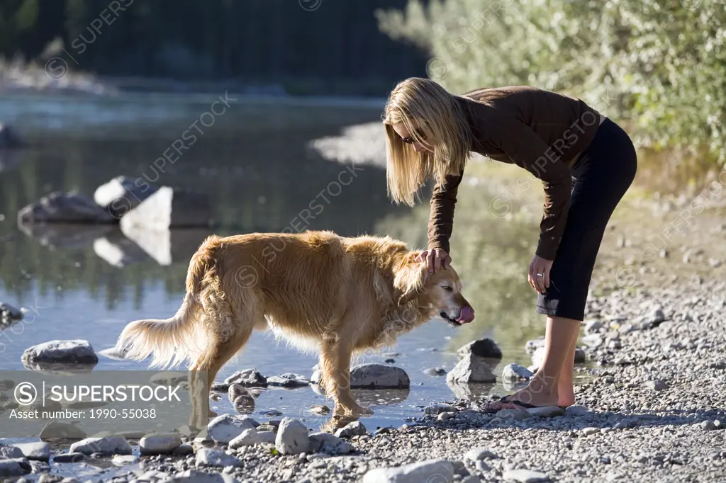 A woman pettinga golden Retriever, Canada.