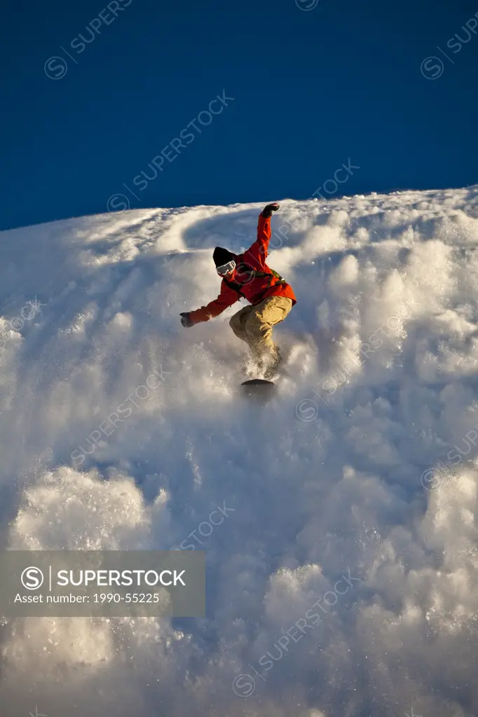 A backcountry snowboarder rides his sluff like a surf wave, Healy Pass, Banff National Park, Alberta, Canada