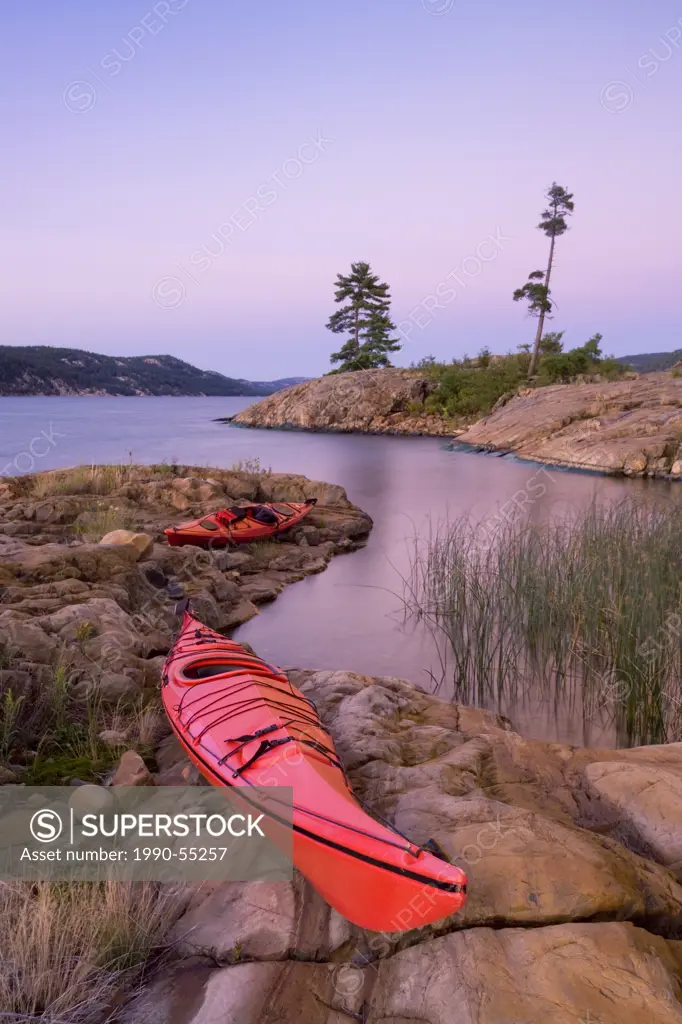 A kayak sits onshore at a protected inlet of Baie Fine at sunset, Killarney Provincial Park, Ontario, Canada.
