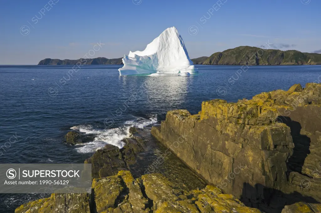 Iceberg floats in Trinity Bay off the rocky shoreline of Bonavista Peninsula in eastern Newfoundland, Newfoundland and Labrador, Canada.