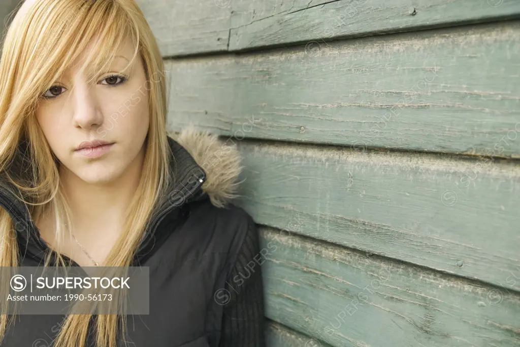 Caucasian female leaning against barn, Alberta, Canada.