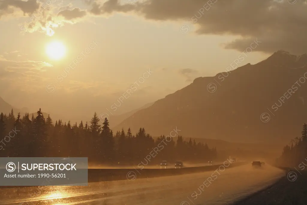 Traffic drives through a dramatic summer rainstorm at sunset along the Trans_Canada Highway in Banff National Park, Alberta, Canada